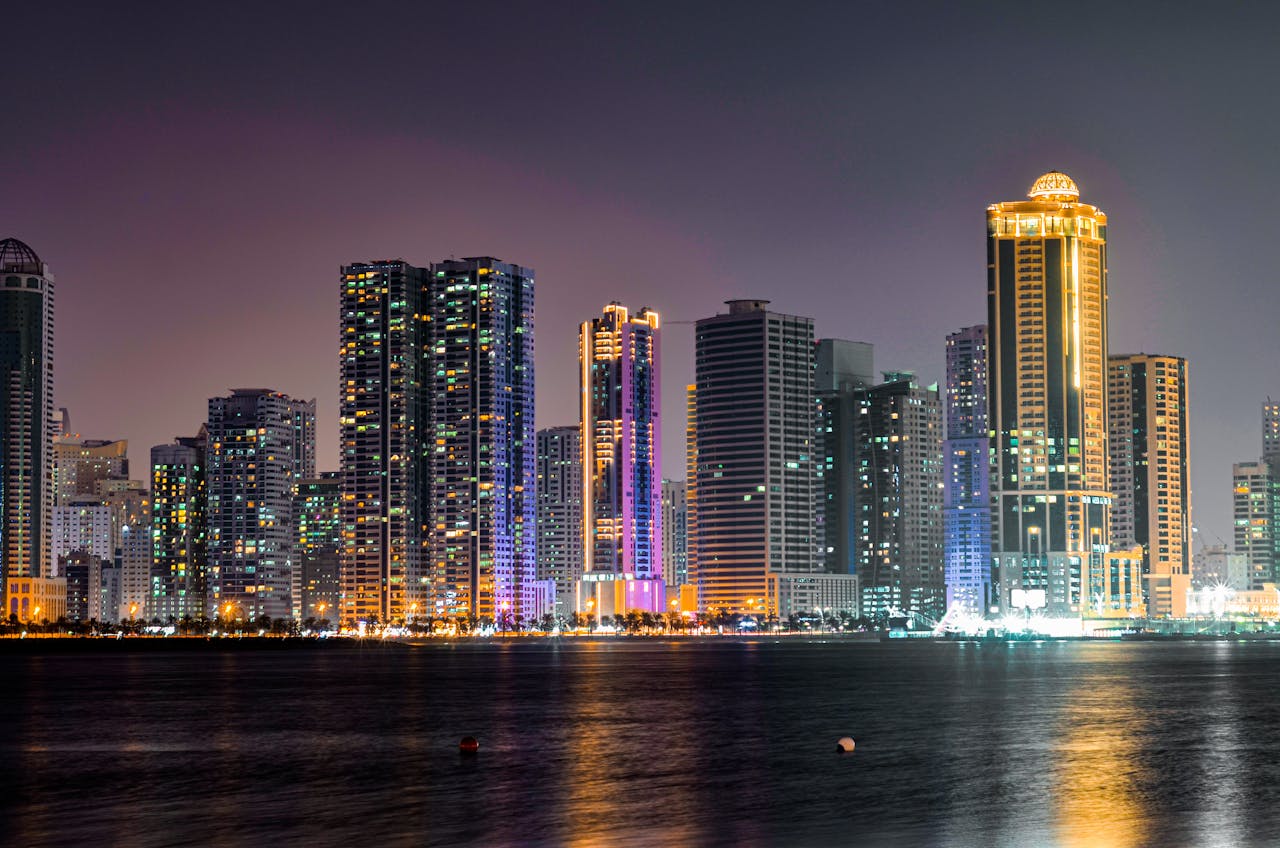 A captivating view of Sharjah's illuminated skyline reflecting on the waterfront at night.