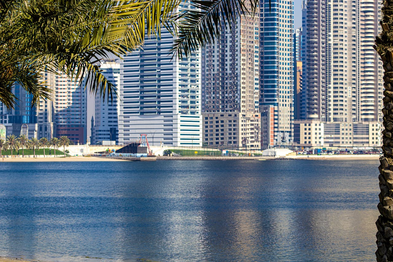 Modern skyscrapers reflecting on the waterfront in Sharjah, UAE.