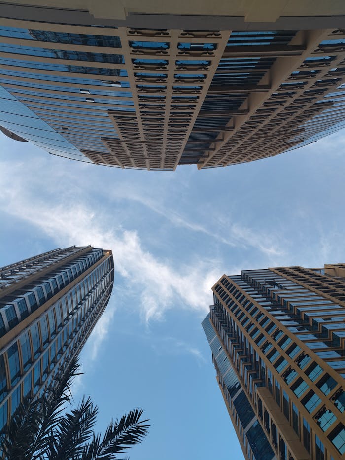 Modern skyscrapers with a blue sky backdrop viewed from ground up.